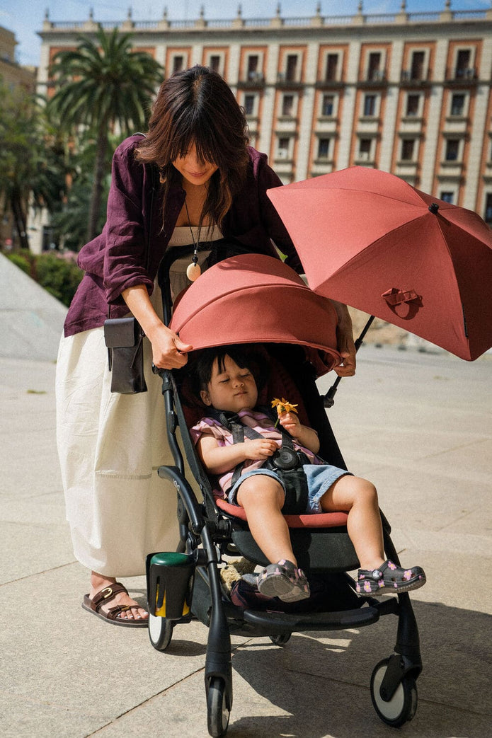 Toddler in a Stokke YOYO stroller shaded by an open Berry YOYO parasol on a sunny walk - Available from Parent Studio.