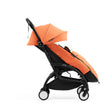 Side profile of the Stokke YOYO5 Stroller and Footmuff in Peach with integrated leg rest, available from Parent Studio.