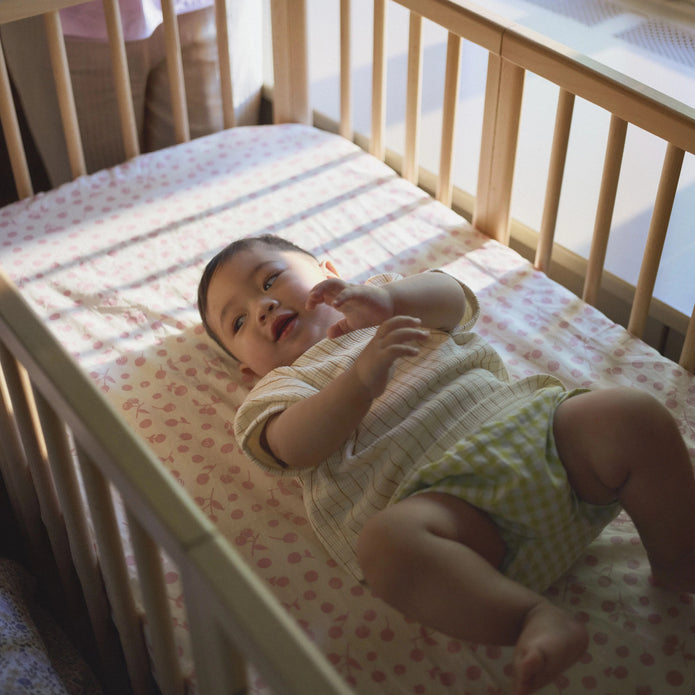 Top-down view of infant laying in the Stokke Nighti Bed on Stokke Nighti fitted sheet - Available from Parent Studio