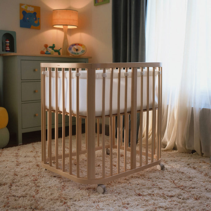 Stokke Nighti Mini Breathable Mesh Liner in white fitted securely inside a natural wooden newborn crib - Available from Parent Studio London