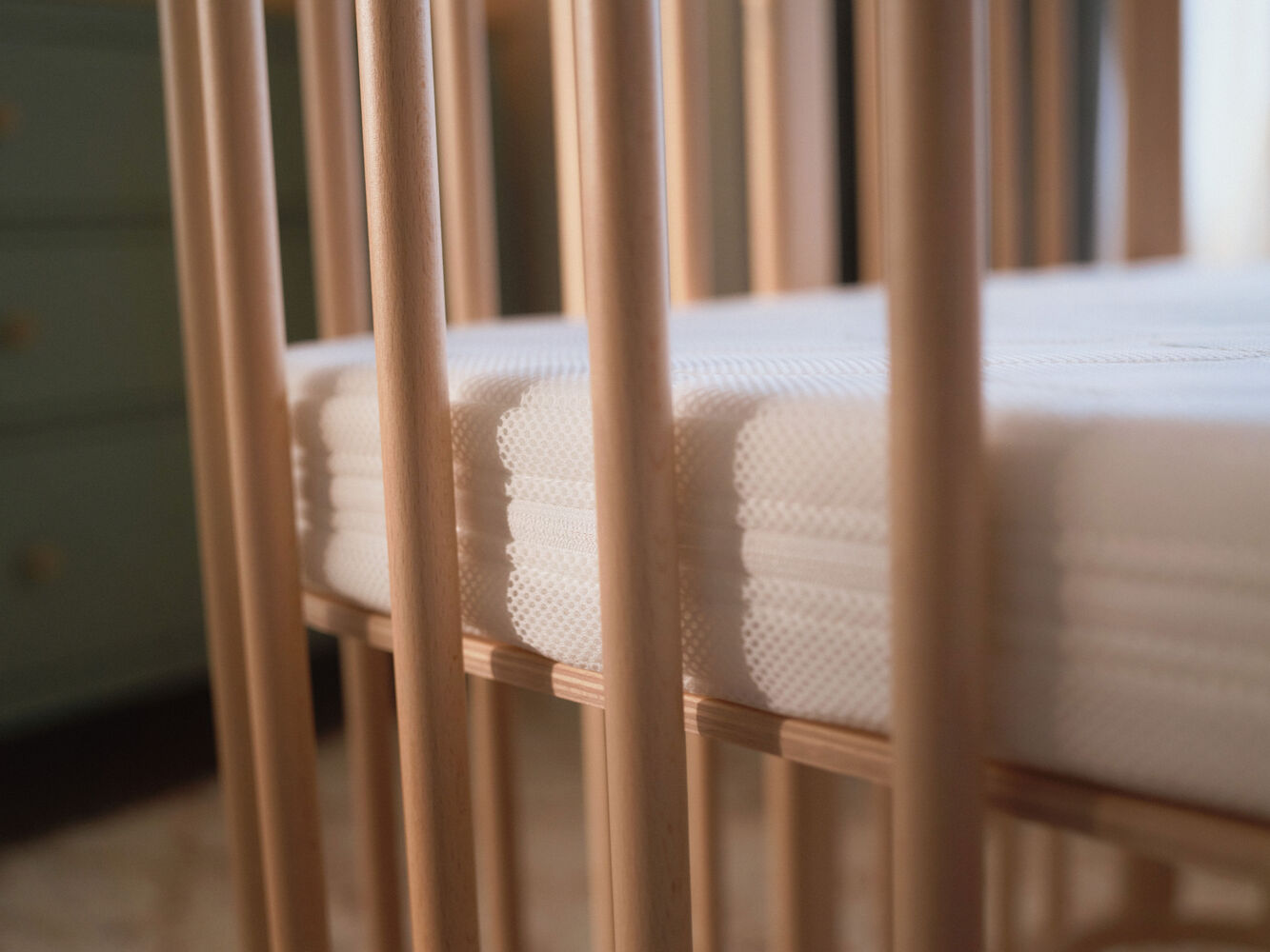Close-up view of the breathable 3D mesh Stokke Nighti Bed Mattress fitted inside the Stokke Nighti natural wooden cot — Available from Parent Studio