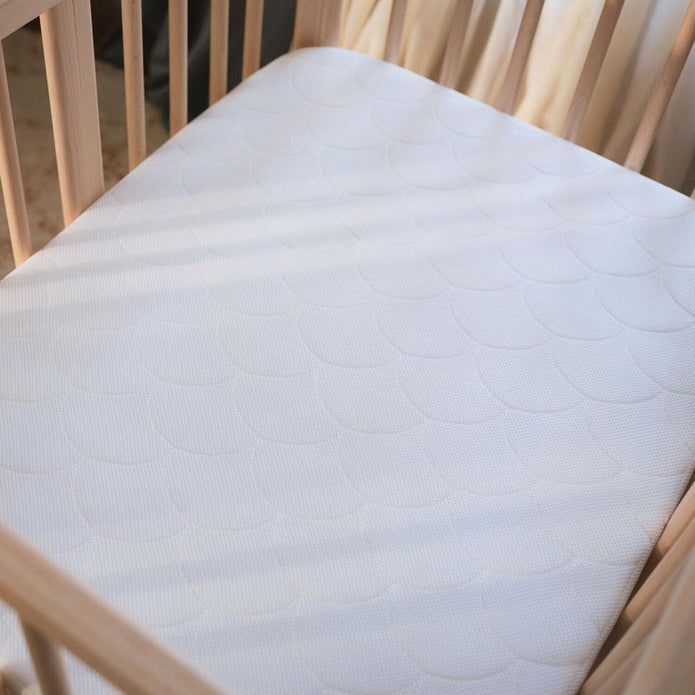 Top view of the breathable 3D mesh Stokke Nighti Bed Mattress fitted inside the Stokke Nighti natural wooden crib — Available from Parent Studio