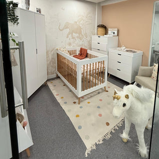 Obaby Nursery room with a crib, dresser, and decorative rug.