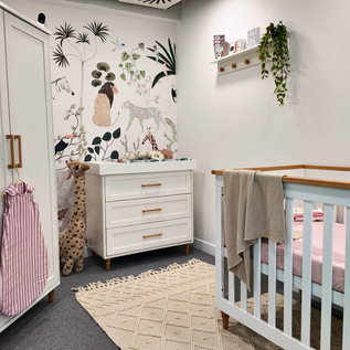 Obaby Nursery room with white dresser, crib, and decorative wall art.