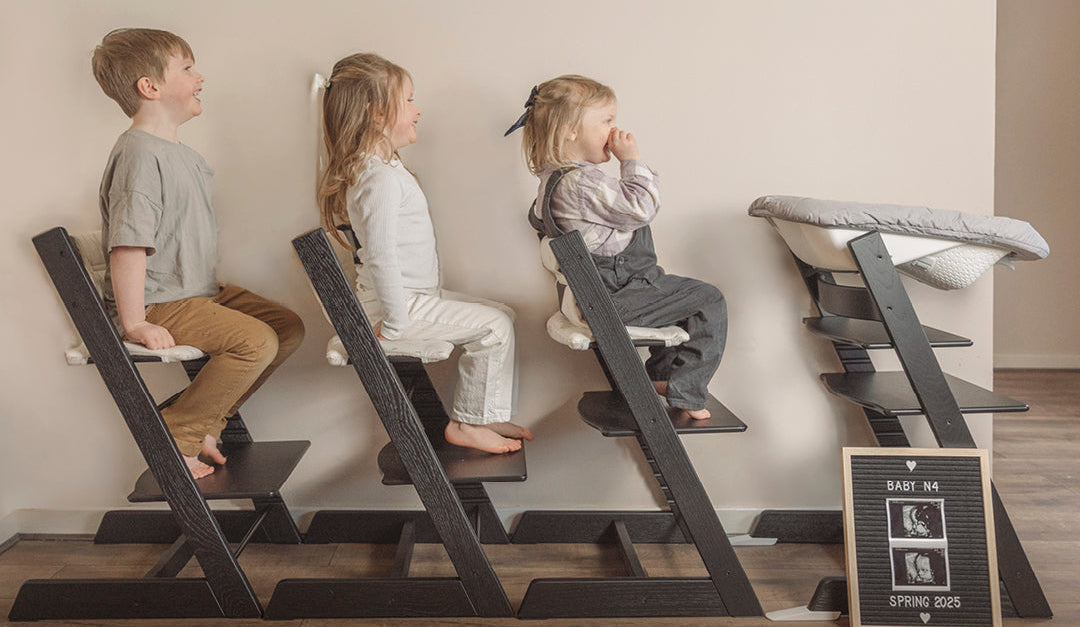 Children sitting on Stokke Tripp Trapp chairs with the brand name displayed.