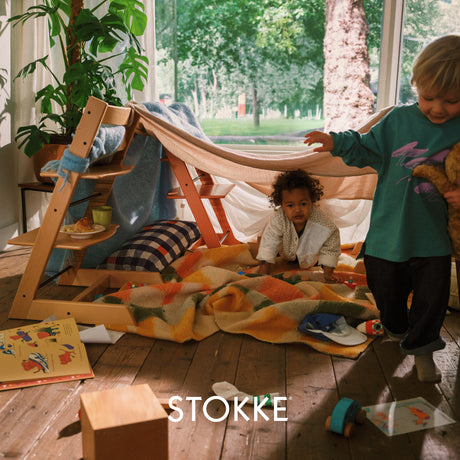 Children playing inside a wooden playhouse with a Stokke logo.