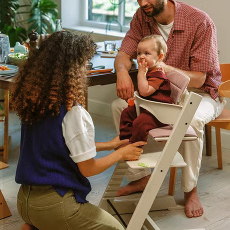 Family with a baby in a high chair at a dining table.