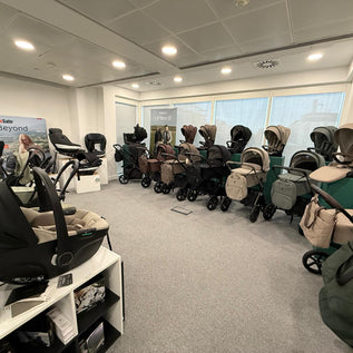 Display of Venicci strollers and car seats in a showroom with large windows.